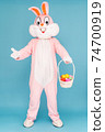 Easter bunny or rabbit or hare with basket of colored eggs, having fun, dancing, celebrates Happy easter. Easter rabbit isolated on blue background 74700919