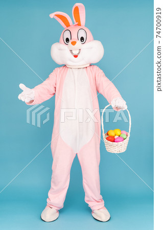 Easter bunny or rabbit or hare with basket of colored eggs, having fun, dancing, celebrates Happy easter. Easter rabbit isolated on blue background 74700919