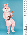 Crazy guitarist is playing music by ukulele or Hawaiian guitar. Easter bunny or rabbit or hare celebrates Happy easter, plays music by instrument. 74700920
