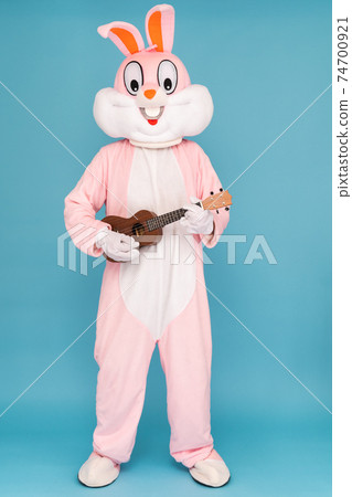Guitar player or guitarist is playing music by ukulele. Easter bunny or rabbit or hare celebrates Happy easter, dancing, plays music by Hawaiian guitar 74700921