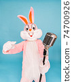 Positive funny man or kid singer or vocalist sings song to retro vintage classic microphone. Easter bunny or rabbit or hare celebrates Happy easter isolated on blue 74700926