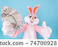 Rich lucky happy man or boy or kid millionaire or billionaire holds fan of dollars, shows thumb finger up, having fun. Easter bunny or rabbit or hare with dollar, celebrate Happy easter 74700928