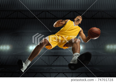 Young professional basketball player in action, motion isolated on black background, look from the bottom. Concept of sport, movement, energy and dynamic. Young professional basketball player in action, motion isolated on black background, look from the bottom. Concept of sport, movement, energy and dynamic. 74701728