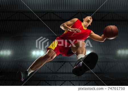 Young professional basketball player in action, motion isolated on black background, look from the bottom. Concept of sport, movement, energy and dynamic. Young professional basketball player in action, motion isolated on black background, look from the bottom. Concept of sport, movement, energy and dynamic. 74701730