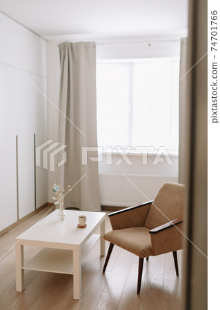 Stylish bright living room with comfortable armchair and table by the window. Stylish bright living room with comfortable armchair and table by the window. 74701766