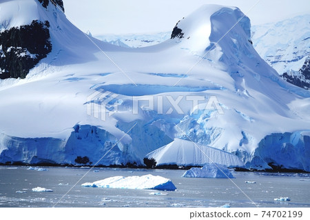 Summer landscape in Antarctica with melting snow, sea, icebergs, mountains. 74702199
