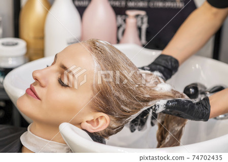 Woman receiving wash her hair Woman receiving wash her hair 74702435
