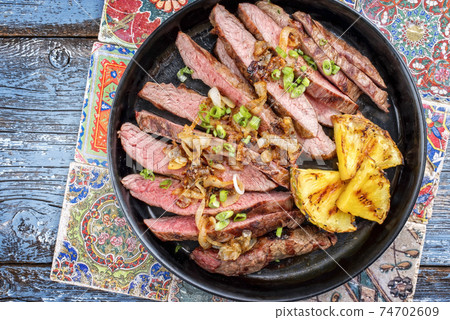 Barbecue dry aged wagyu flank steak with pineapples and onion rings  74702609