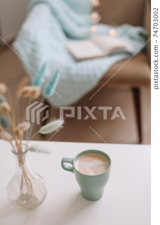 Cozy home interior with cup of coffee, book and armchair 74703002