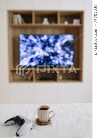 Game controller, joystick on TV screen background. Playing game console, weekend at home, leisure lifestyle concept Game controller, joystick on TV screen background. Playing game console, weekend at home, leisure lifestyle concept 74703039