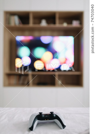 Game controller, joystick on TV screen background. Playing game console, weekend at home, leisure lifestyle concept Game controller, joystick on TV screen background. Playing game console, weekend at home, leisure lifestyle concept 74703040