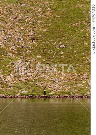 Beautiful and picturesque Carpathian lake Brebeneskul, a guy on the edge of the lake, the edge of the mighty mountains, a lake in the valley. Beautiful and picturesque Carpathian lake Brebeneskul, a guy on the edge of the lake, the edge of the mighty mountains, a lake in the valley. 74704330