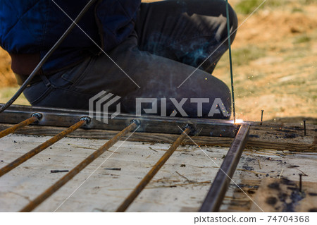 Welding a metal profile at home, a man welds metal to design an aviary for a dog. Welding a metal profile at home, a man welds metal to design an aviary for a dog. 74704368