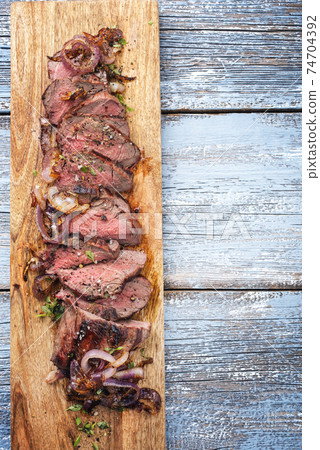 barbecue dry aged sliced roast beef with fried onion rings as top view 74704392