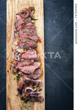 Traditional barbecue dry aged sliced roast beef with fried onion rings 74704404