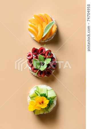 Rice cakes with different types garnish fruits, vegetables, microgreens on natural beige background. Banner. 74704958