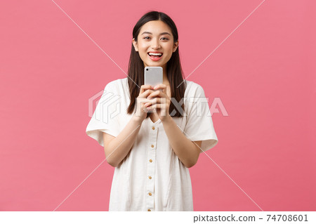 Beauty, people emotions and technology concept. Smiling happy asian female blogger, stylish girl taking photo on smartphone, looking upbeat as photographing, taking picture with mobile phone 74708601