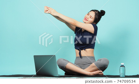 Fitness influencer. Sporty woman workout training online via laptop. copy space. blue green background. Athletic woman blogger in sportswear shoots video on notebook camera as exercises at home. Exerc Fitness influencer. Sporty woman workout training online via laptop. copy space. blue green background. Athletic woman blogger in sportswear shoots video on notebook camera as exercises at home. Exerc 74709534