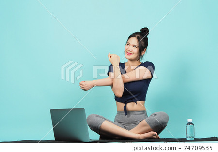 Fitness influencer. Sporty woman workout training online via laptop. copy space. blue green background. Athletic woman blogger in sportswear shoots video on notebook camera as exercises at home. Exerc Fitness influencer. Sporty woman workout training online via laptop. copy space. blue green background. Athletic woman blogger in sportswear shoots video on notebook camera as exercises at home. Exerc 74709535