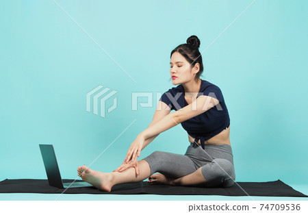 Fitness influencer. Sporty woman workout training online via laptop. copy space. blue green background. Athletic woman blogger in sportswear shoots video on notebook camera as exercises at home. Exerc Fitness influencer. Sporty woman workout training online via laptop. copy space. blue green background. Athletic woman blogger in sportswear shoots video on notebook camera as exercises at home. Exerc 74709536