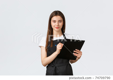 Grocery store employees, small business and coffee shops concept. Shop manager checking products in stock, writing down items on clipboard, wearing black apron uniform, white background 74709790