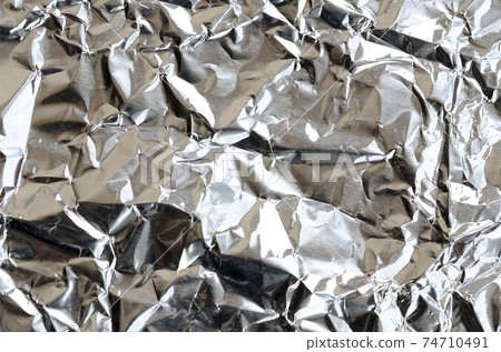 Thin wrinkled sheet of crushed tin aluminum silver foil background with shiny crumpled surface for texture Thin wrinkled sheet of crushed tin aluminum silver foil background with shiny crumpled surface for texture 74710491
