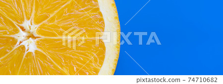 Top view of a one orange fruit slice on bright background in blue color. A saturated citrus texture image Top view of a one orange fruit slice on bright background in blue color. A saturated citrus texture image 74710682
