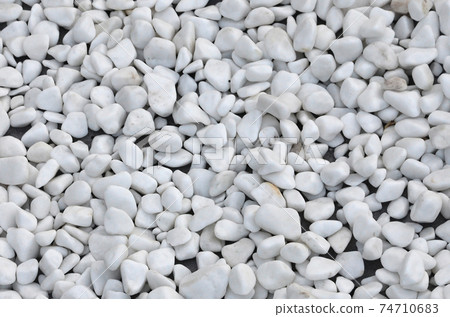 A lot of round and oval stones of white color lie on the ground in the garden A lot of round and oval stones of white color lie on the ground in the garden 74710683