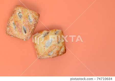 A satisfying meat patty, which combines an airy puff pastry and a delicate pork filling with onions. Baking on an orange background A satisfying meat patty, which combines an airy puff pastry and a delicate pork filling with onions. Baking on an orange background 74710684