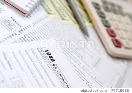 The pen, notebook, calculator, and dollar bills is lies on the tax form 1040 U.S. Individual Income Tax Return. The time to pay taxes The pen, notebook, calculator, and dollar bills is lies on the tax form 1040 U.S. Individual Income Tax Return. The time to pay taxes 74710686