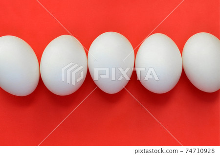 A few white eggs on a bright red background A few white eggs on a bright red background 74710928