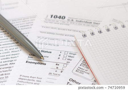 The pen and notebook is lies on the tax form 1040 U.S. Individual Income Tax Return. The time to pay taxes The pen and notebook is lies on the tax form 1040 U.S. Individual Income Tax Return. The time to pay taxes 74710959