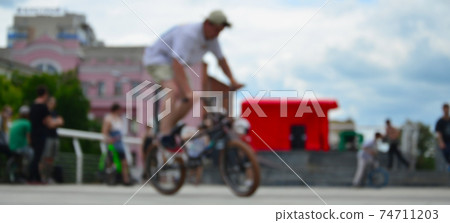 Defocused image of a lot of people with bmx bikes. Meeting of fans of extreme sports Defocused image of a lot of people with bmx bikes. Meeting of fans of extreme sports 74711203