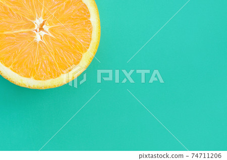 Top view of a one orange fruit slice on bright background in turquoise green color. A saturated citrus texture image Top view of a one orange fruit slice on bright background in turquoise green color. A saturated citrus texture image 74711206