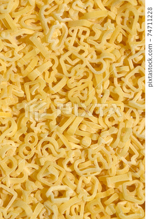 Texture of a lot of curly raw yellow pasta 74711228