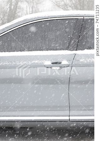 Fragment of the car under a layer of snow after a heavy snowfall. The body of the car is covered with white snow 74711235