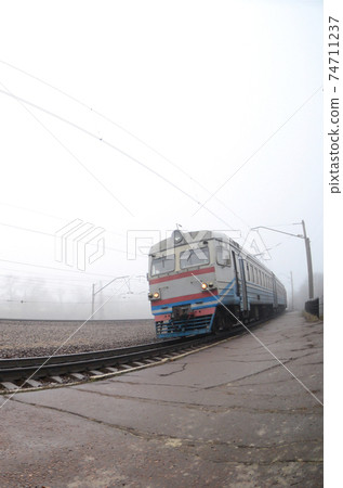 The Ukrainian suburban train rushes along the railway in a misty morning. Fisheye photo with increased distortion 74711237