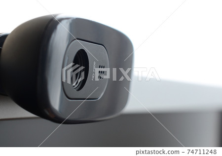 A modern web camera is installed on the body of a flat screen monitor. Device for video communication and recording of high quality video 74711248