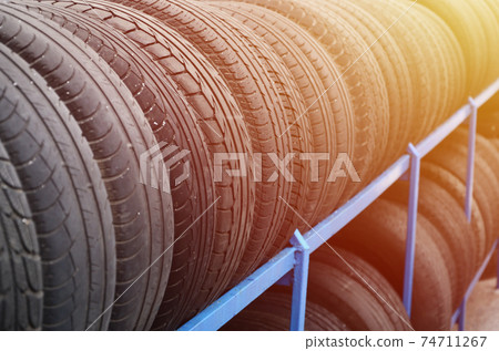 Rack with variety of car tires in automobile store. Many black tires. Tire stack background. Selective focus Rack with variety of car tires in automobile store. Many black tires. Tire stack background. Selective focus 74711267