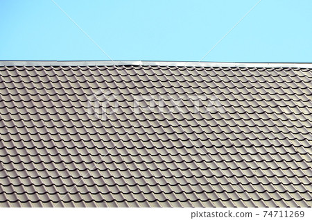 A fragment of a roof from a metal tile of dark red color. Quality Roofing A fragment of a roof from a metal tile of dark red color. Quality Roofing 74711269