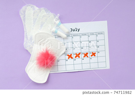 Menstrual pads and tampons on menstruation period calendar flat lay on lilac background Menstrual pads and tampons on menstruation period calendar flat lay on lilac background 74711982