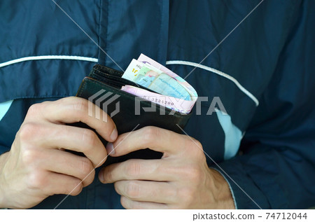 Man holds in hands black leather wallet with ukrainian money or thief who stole wallet full of money Man holds in hands black leather wallet with ukrainian money or thief who stole wallet full of money 74712044