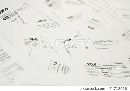 Many tax form blanks lies on table close up. Tax payers paperwork routine and bureaucracy concept Many tax form blanks lies on table close up. Tax payers paperwork routine and bureaucracy concept 74712056