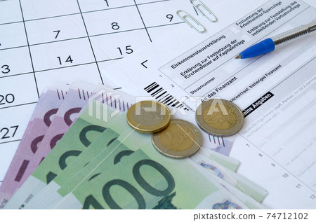 German tax form with pen and european money bills lies on office calendar. Taxpayers in Germany using euro currency to pay taxes German tax form with pen and european money bills lies on office calendar. Taxpayers in Germany using euro currency to pay taxes 74712102