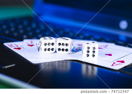 Online gaming platform, casino and gambling business. Cards, dice and multi-colored game pieces on laptop keyboard Online gaming platform, casino and gambling business. Cards, dice and multi-colored game pieces on laptop keyboard 74712347