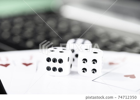 Online gaming platform, casino and gambling business. Cards, dice and multi-colored game pieces on laptop keyboard Online gaming platform, casino and gambling business. Cards, dice and multi-colored game pieces on laptop keyboard 74712350
