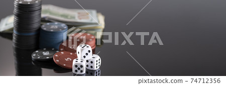 Chips, cards and dice for a casino game on a black background with reflection. The concept of gambling and entertainment. Casino and poker 74712356