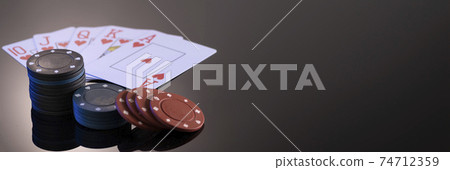 Chips and cards for playing in a casino on a black background with reflection. The concept of gambling and entertainment. Casino and poker Chips and cards for playing in a casino on a black background with reflection. The concept of gambling and entertainment. Casino and poker 74712359