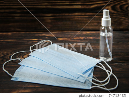 bottle of disinfectant liquid and three medical masks on a wooden table 74712485