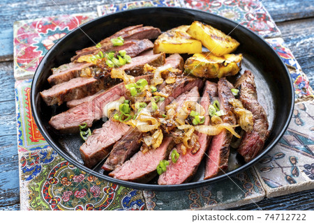 Barbecue dry aged wagyu flank steak with pineapples and onion rings 74712722